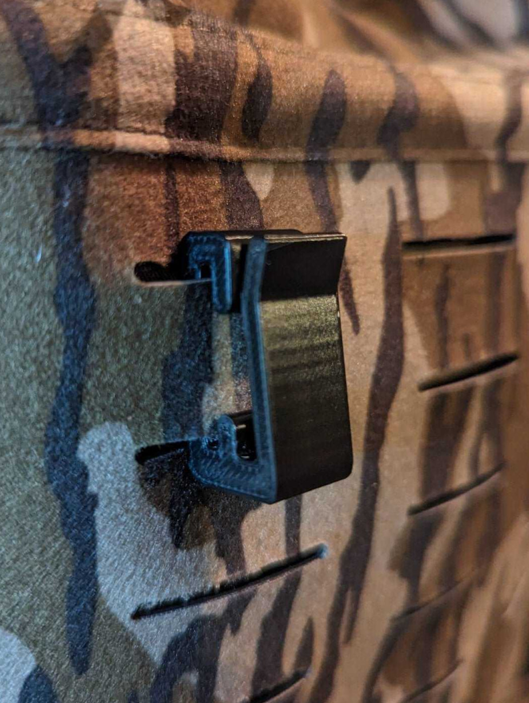 3D Hunting Solutions Molle hook hanger for tactical gear, shown attached to a molle webbing system in a close-up view.