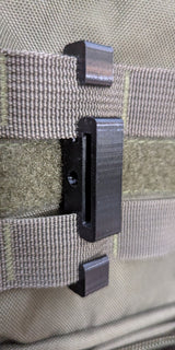3D Hunting Solutions Molle Reverser Clip attached to climbing sticks for secure gear attachment and easy access during hunting.