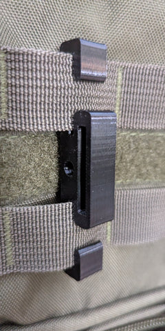 3D Hunting Solutions Molle Reverser Clip attached to climbing sticks for secure gear attachment and easy access during hunting.