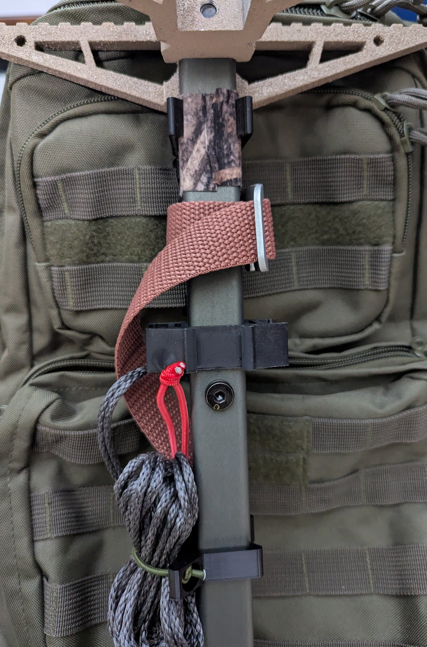 3D Hunting Solutions Molle Reverser Clip attached to climbing sticks, showcasing durable metal construction for secure gear attachment.