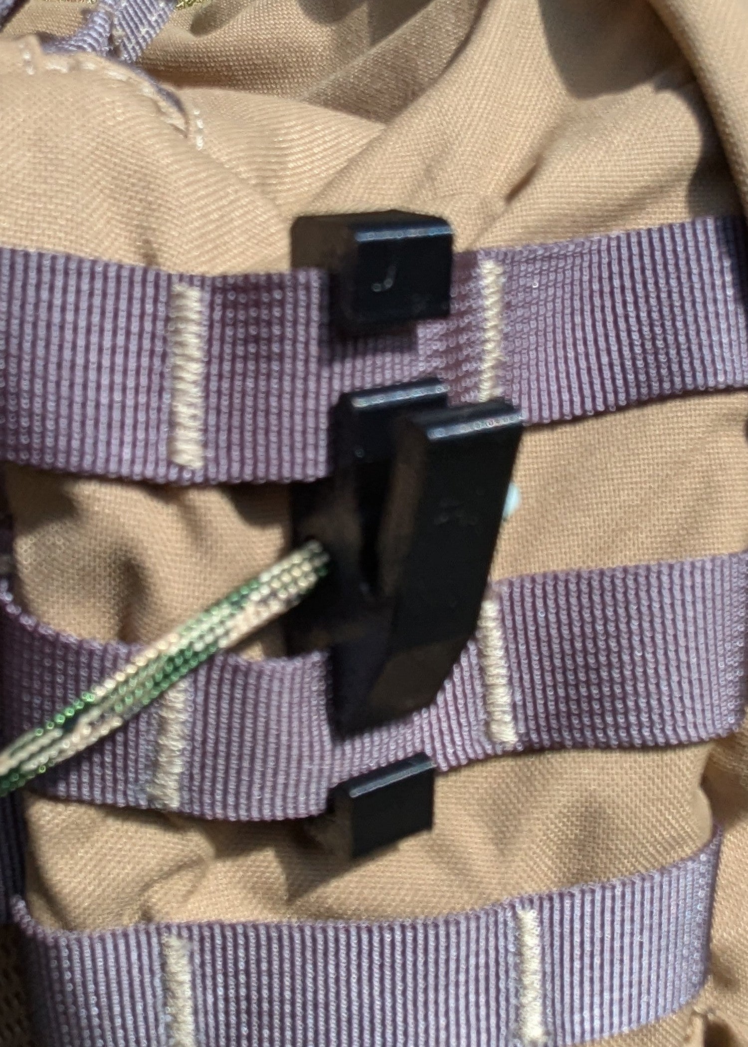3D Hunting Solutions Molle Reverser Clip attached to climbing sticks for secure gear attachment in outdoor climbing and hunting setups.