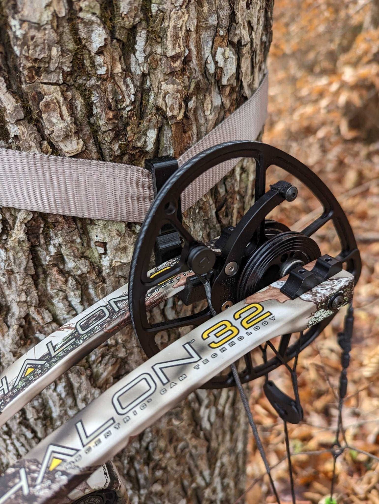 Split limb bow hanger gear strap for saddle hunting by 3D Hunting Solutions, shown attached to a tree branch with a bow.