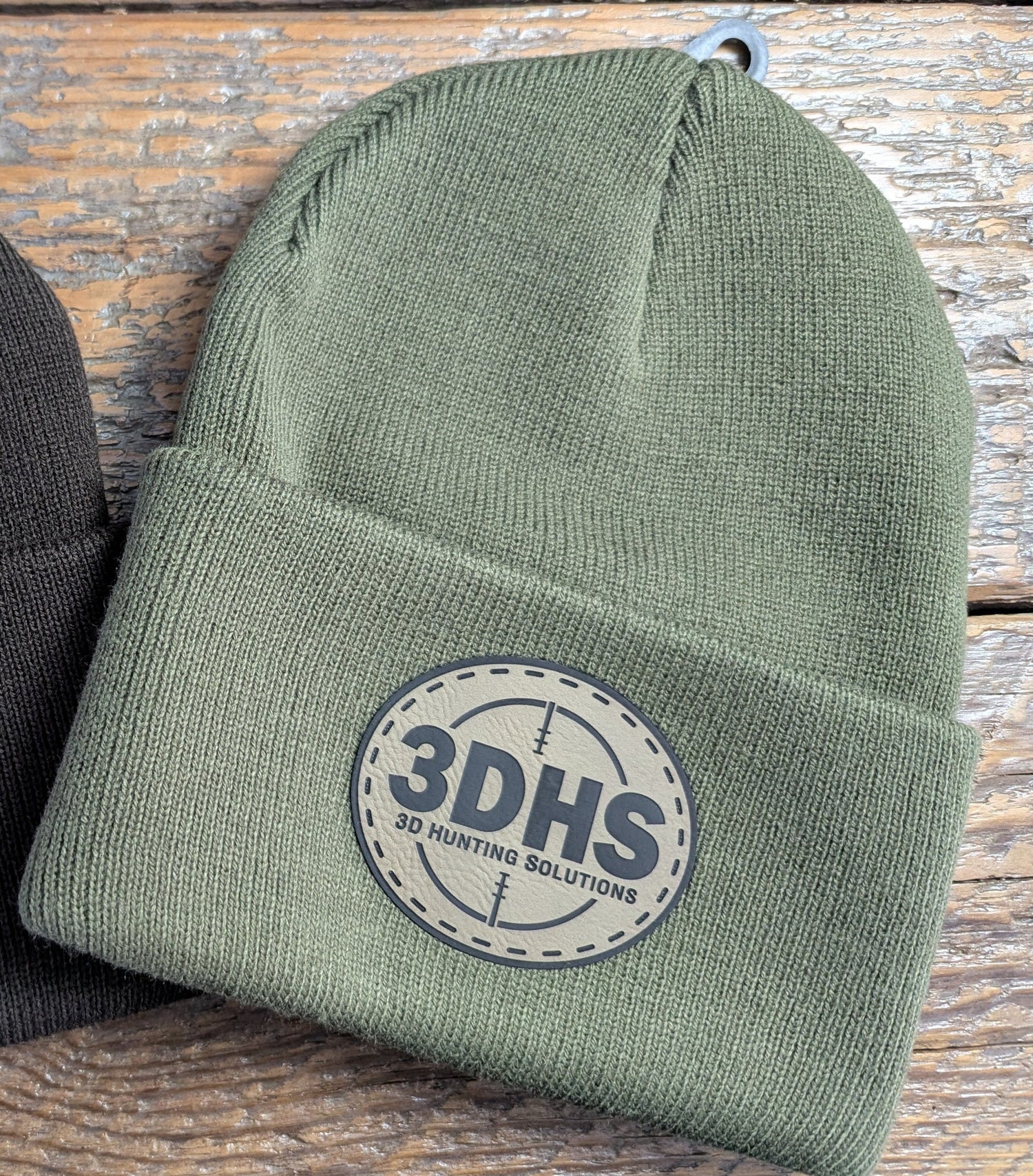 Brown 3DHS Crosshair Beanie hat by 3D Hunting Solutions, featuring a knitted design and crosshair logo for outdoor wear.