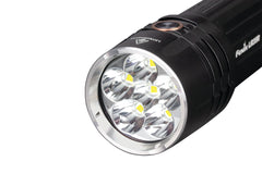 Fenix LR35R rechargeable LED flashlight with 10,000 lumens, black body, and adjustable focus, shown turned on in a dark setting.